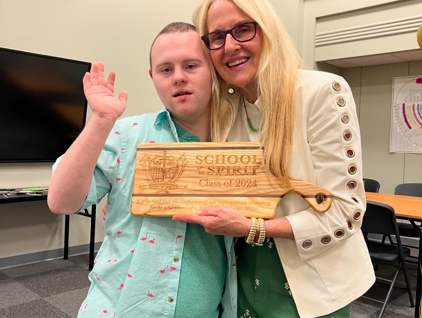 Rosemary and a graduate holding their custom School of Spirit cheese board from Stone Wall Woodworks